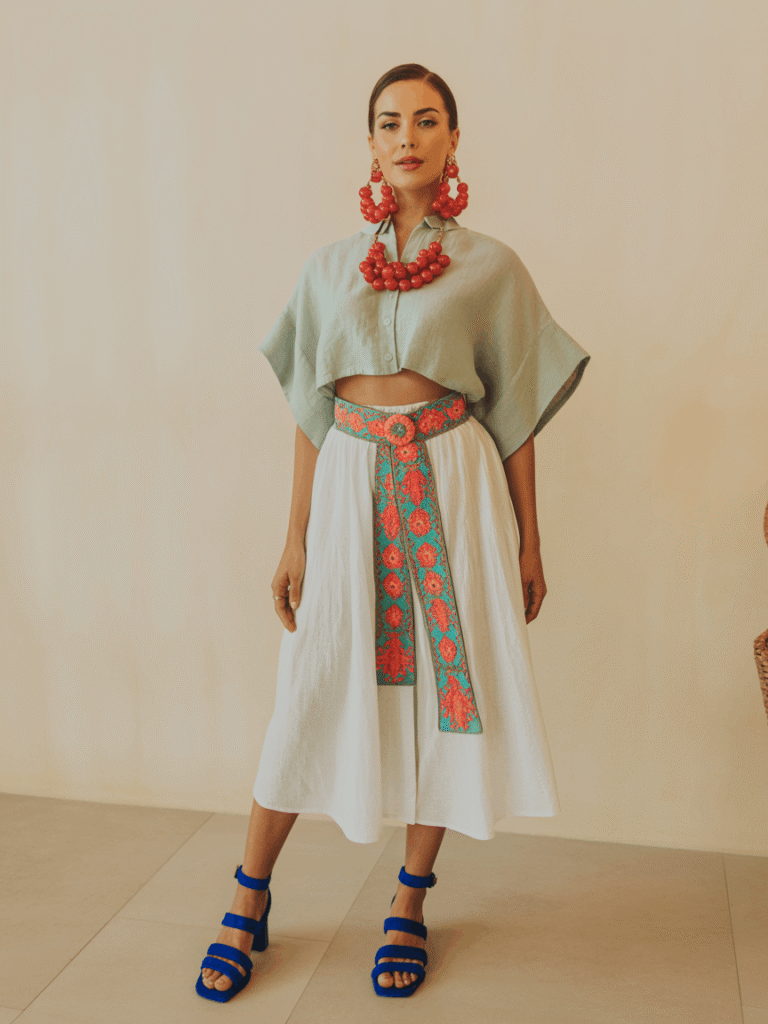 31 Cinco de Mayo Outfits Women Will Love (Because Life's Too Short to Wear Boring Colors) 8 Woman wearing a cropped linen blouse with a white midi skirt and colorful accessories for a fresh daytime Cinco de Mayo outfit