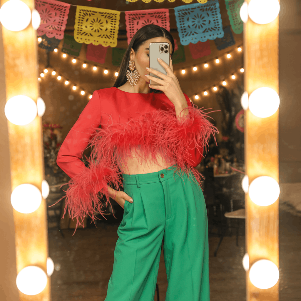 35 Cinco de Mayo Outfit Women Guide: Dress for Your Vibe, Not Just the Holiday 15 Woman wearing a feather-trim top tucked into high-waisted wide-leg trousers, styled with platform heels and dramatic earrings for a bold festive party outfit.