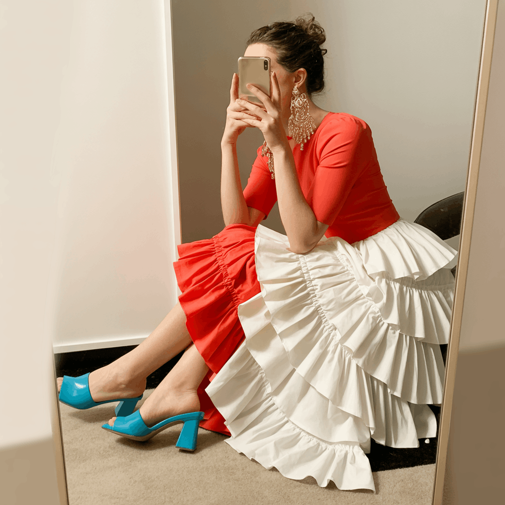 35 Cinco de Mayo Outfit Women Guide: Dress for Your Vibe, Not Just the Holiday 19 Woman wearing a two-tone ruffle dress with a red bodice and contrasting ruffled skirt, styled with colorful heeled mules and chandelier earrings for a dramatic festive party look