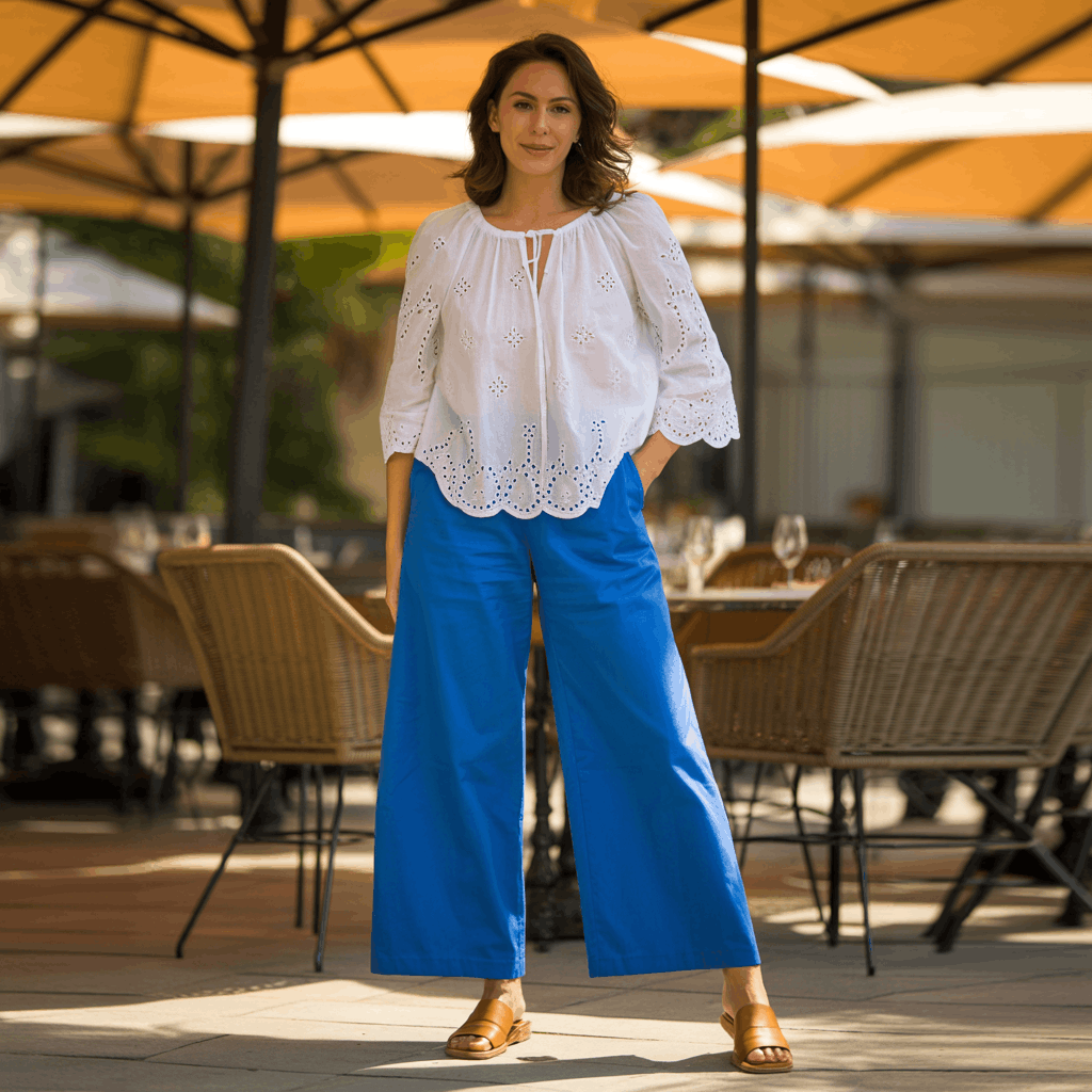 31 Cinco de Mayo Outfits Women Will Love (Because Life's Too Short to Wear Boring Colors) 6 Woman wearing a white peasant blouse tucked into bright wide-leg pants with flat mules for a chic brunch-ready Cinco de Mayo outfit