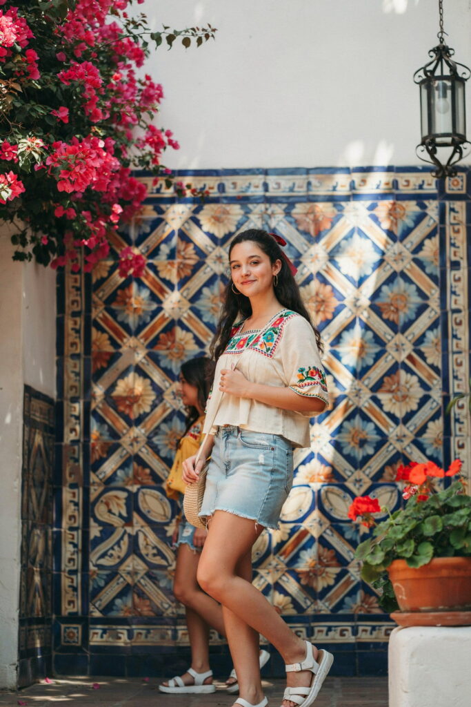 21 Cinco de Mayo Outfit Ideas for Teens That Look Cute and Seriously Trendy 10 Teen wearing a light-wash denim mini skirt with a colorful embroidered white top and white sneakers for a stylish, age-appropriate Cinco de Mayo outfit.