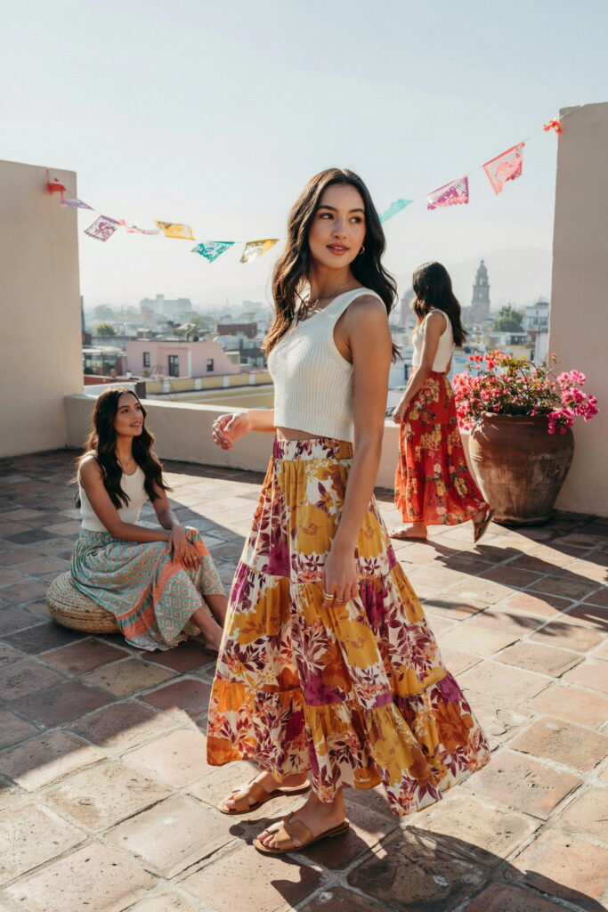 21 Cinco de Mayo Outfit Ideas for Teens That Look Cute and Seriously Trendy 21 Teen wearing a neutral ribbed knit crop top with a bold, colorful printed maxi skirt, flat leather sandals, and stacked rings for a stylish Cinco de Mayo outfit.