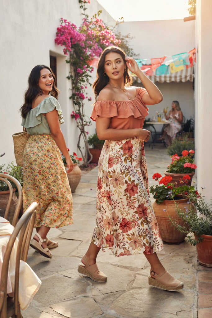 Curvy woman wearing an off-shoulder ruffled top with a floral A-line maxi skirt and espadrille wedges for a chic Cinco de Mayo outfit.